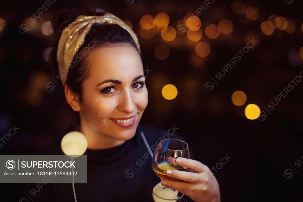 Portrait of smiling woman with drink wearing golden hair-band