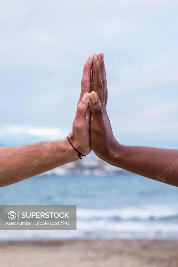 Close-up of two hands touching on the beach