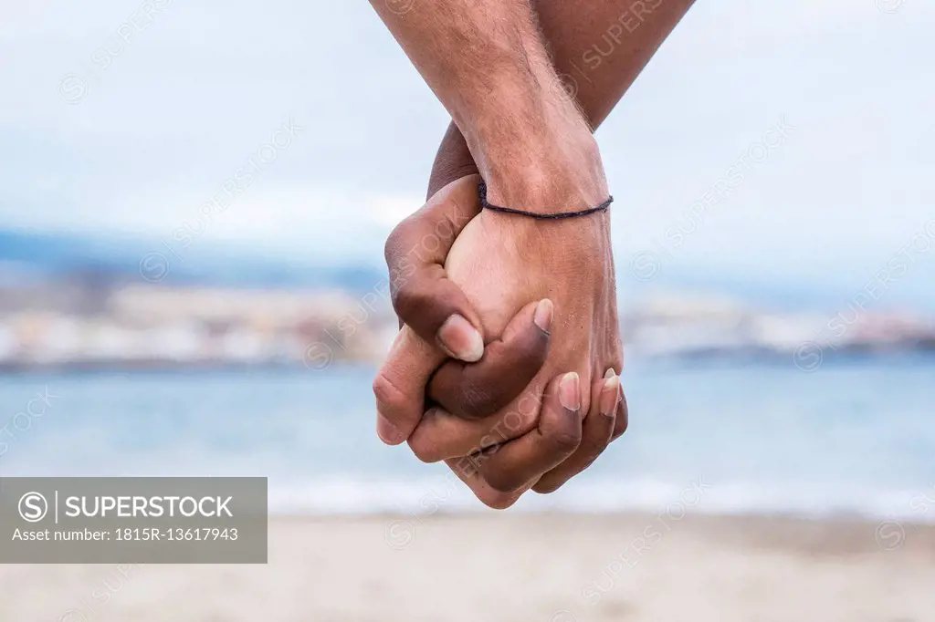 Close-up of two hands connected on the beach