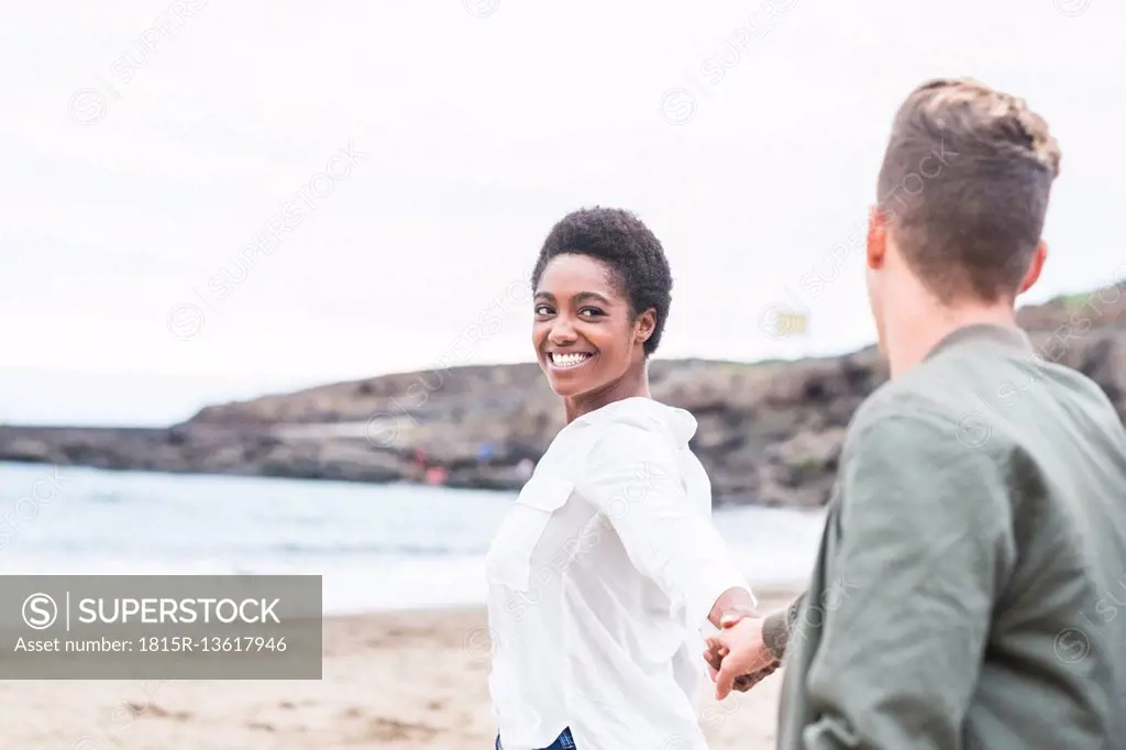 Happy young couple walking hand in hand on the beach