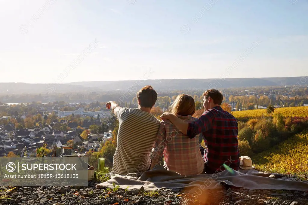 Friends sitting on a hill above a town