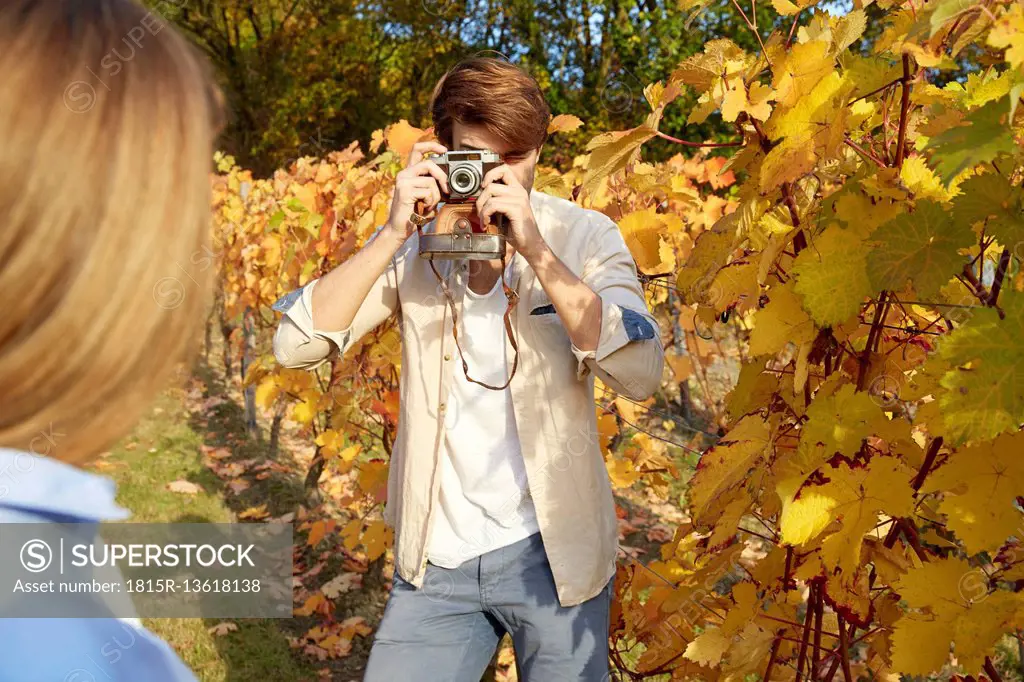 Man taking picture of woman in a vineyard