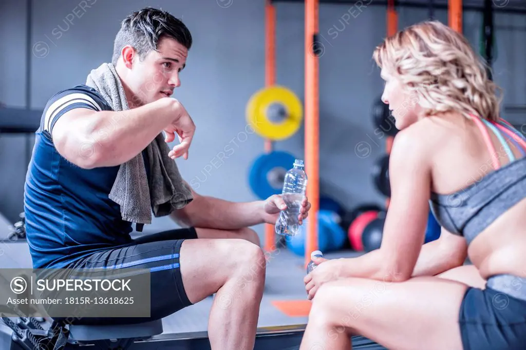 Young man and woman having a refreshment break in gym