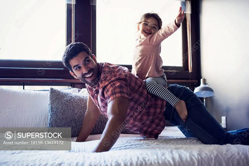 Father and daughter playing on bed