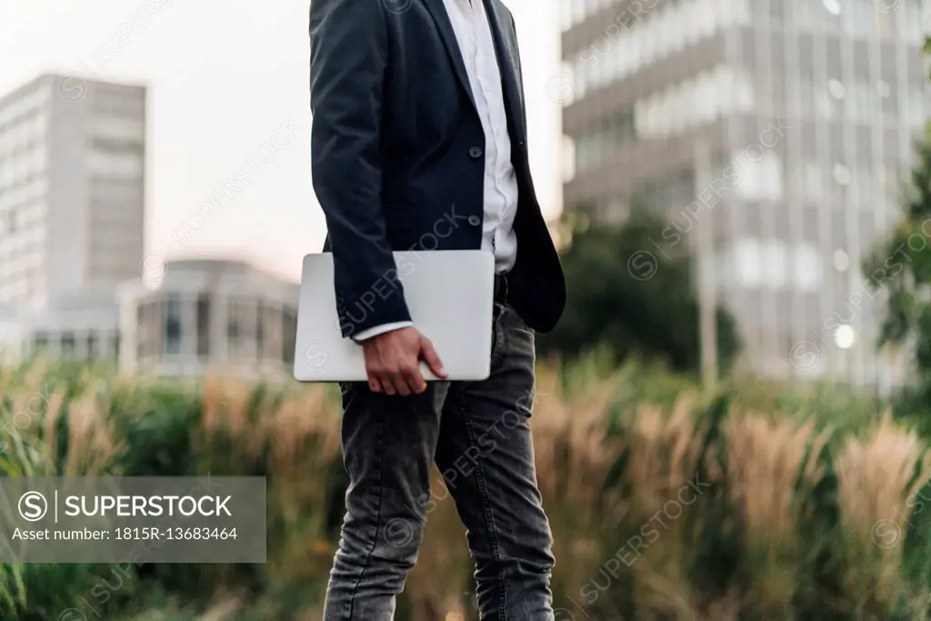 Businessman holding laptop outdoors