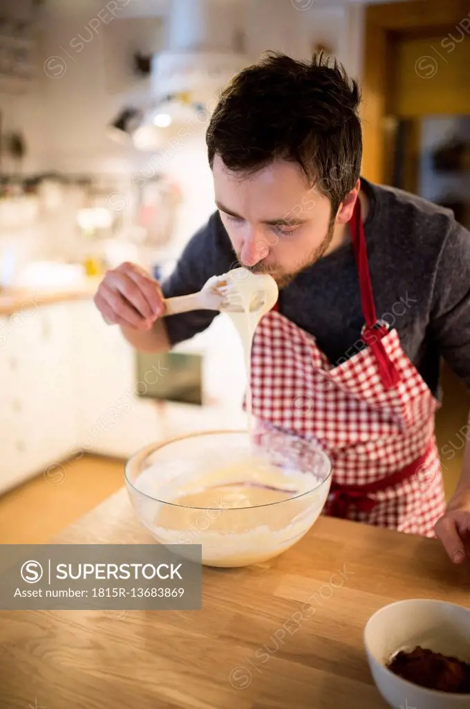 Man standing in kitchen, preparing cake dough
