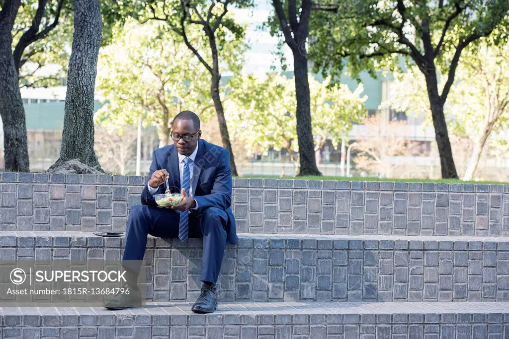Businessman sitting on outdoor stairs having lunch