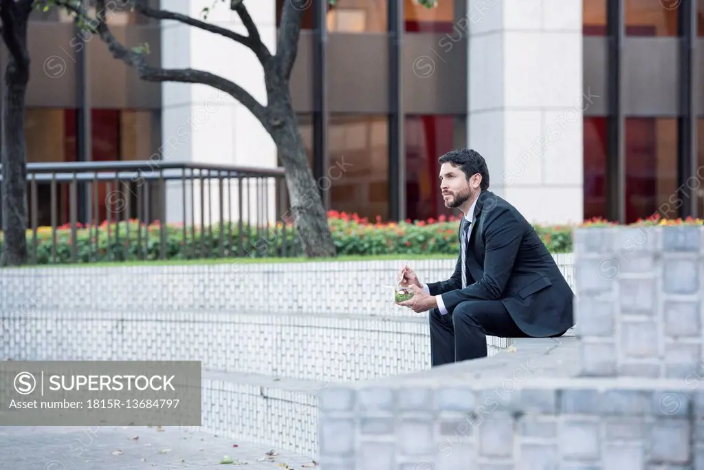 Businessman sitting on outdoor stairs having lunch
