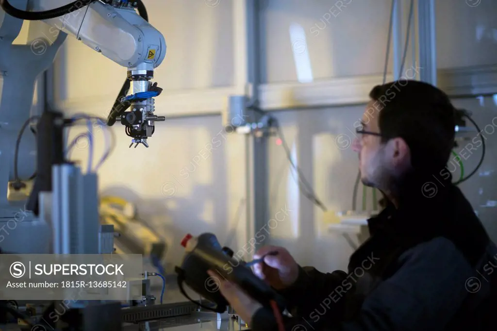 Man looking at robot arm in a sensor technology plant