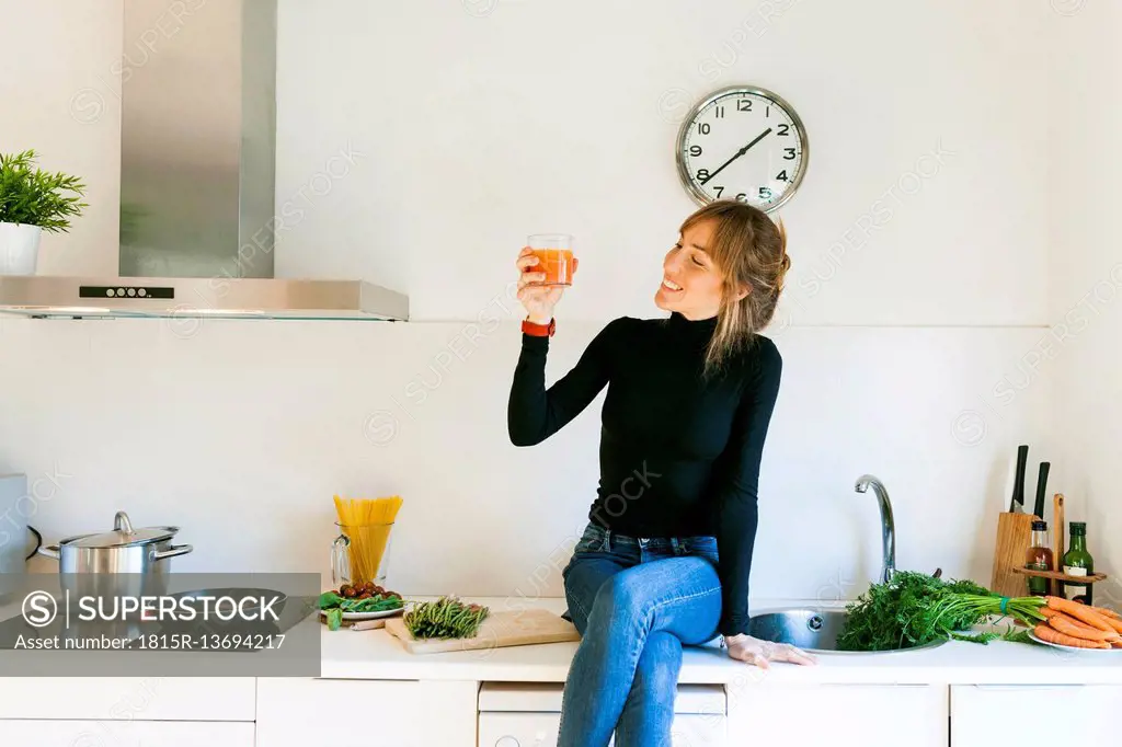 Young woman drinking fresh grapefruit juice in her kitchen
