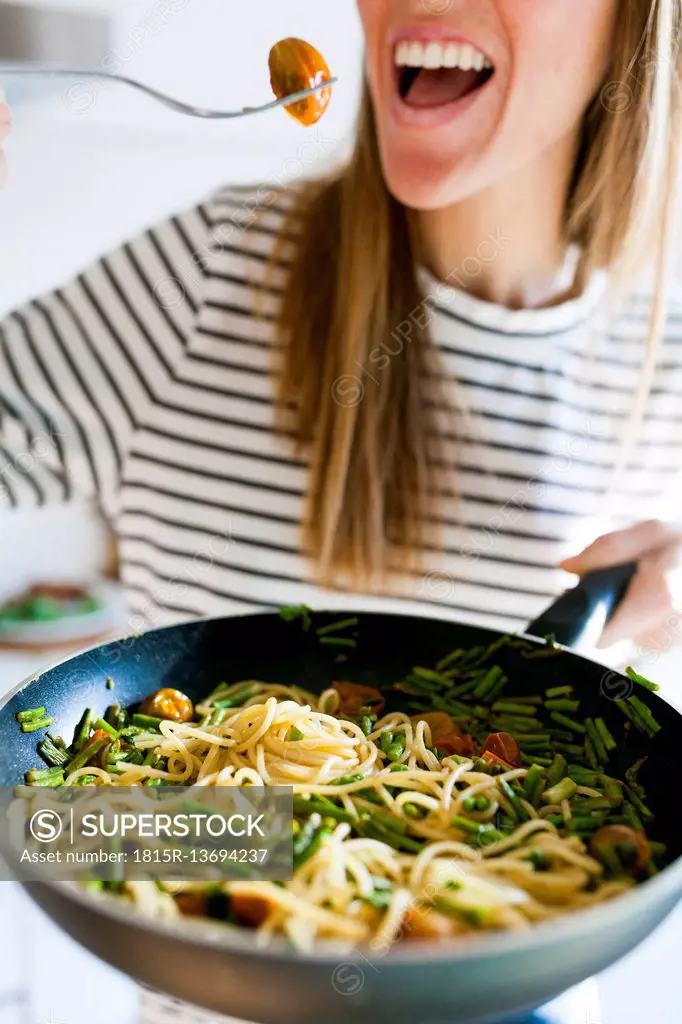 Young woman holding pan with vegan pasta dish