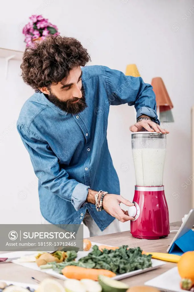 Man preparing smoothie with fresh fruits and vegetables at home