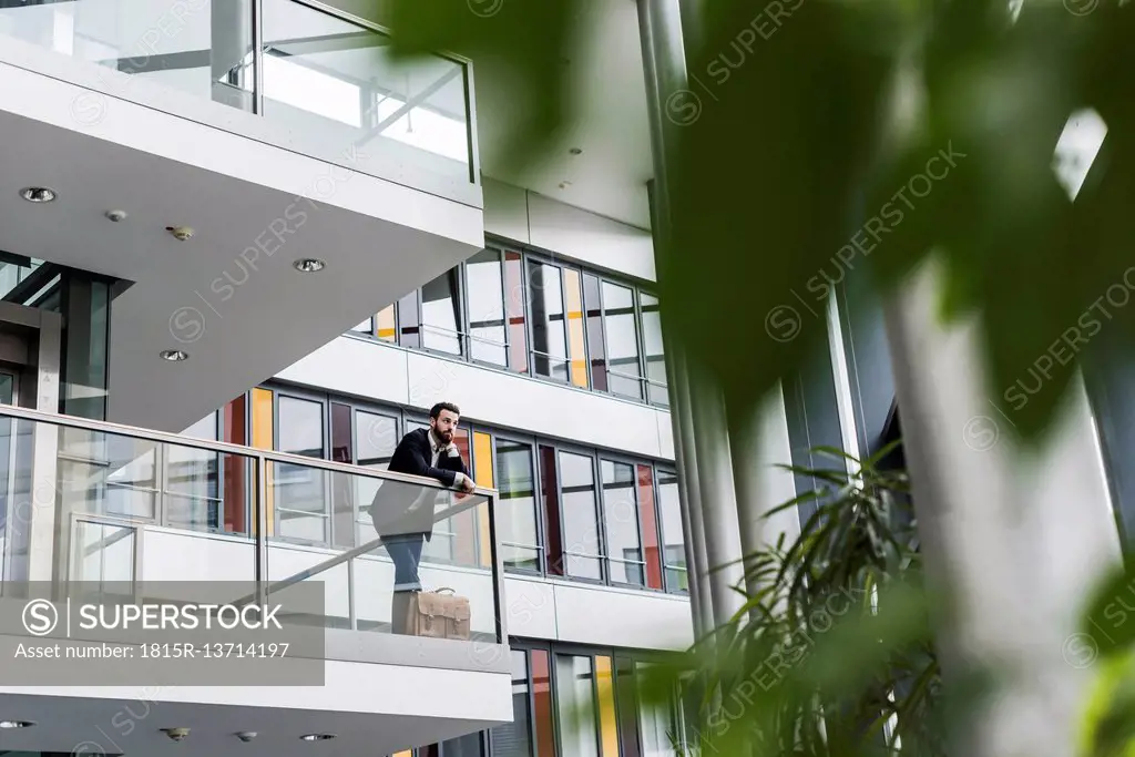 Businessman standing in office building, thinking