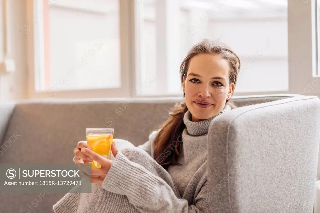 Portrait of woman sitting on couch holding fresh drink