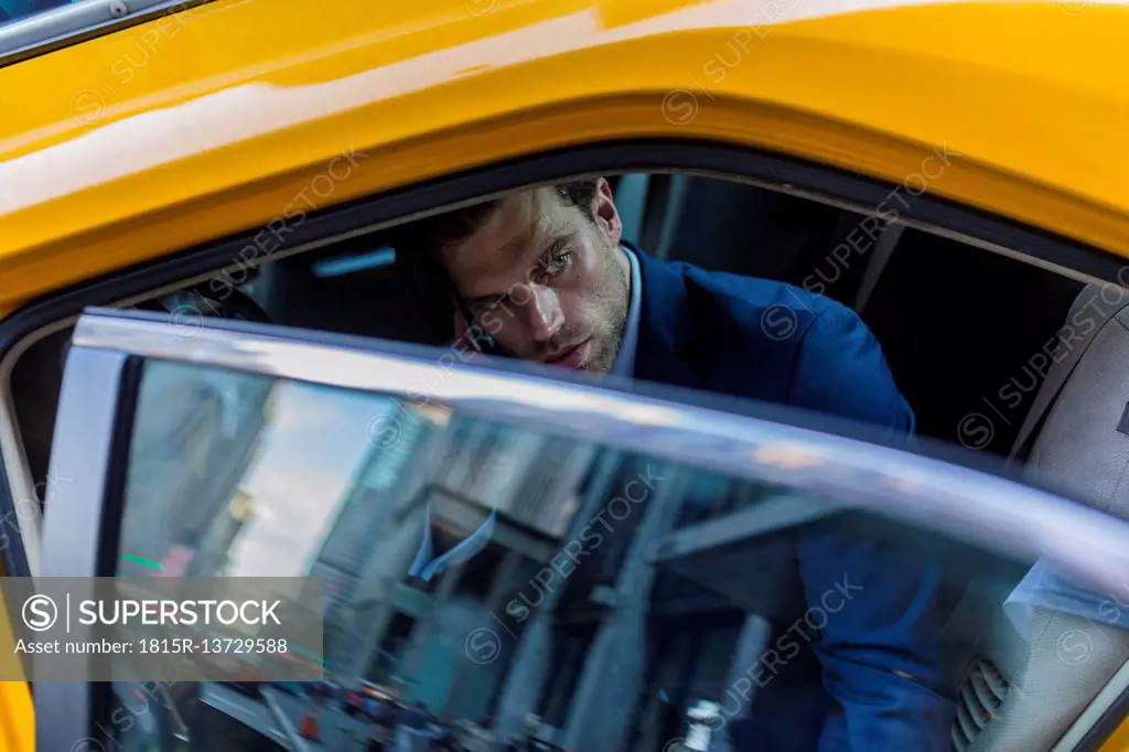 Businessman sitting in taxi, using smart phone