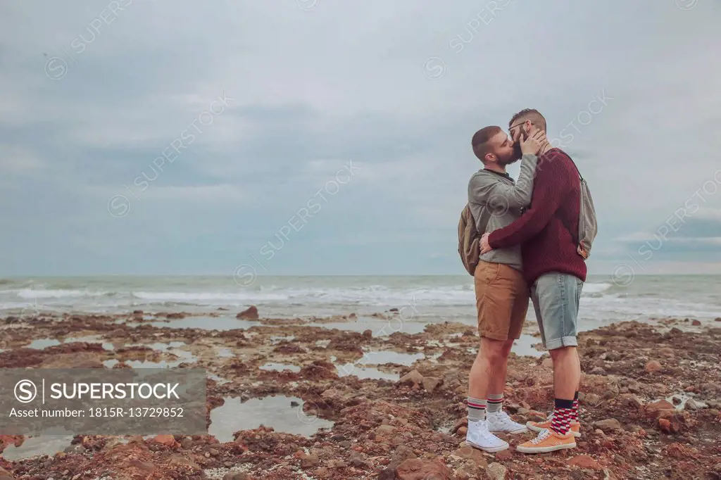 Young gay couple kissing on the beach