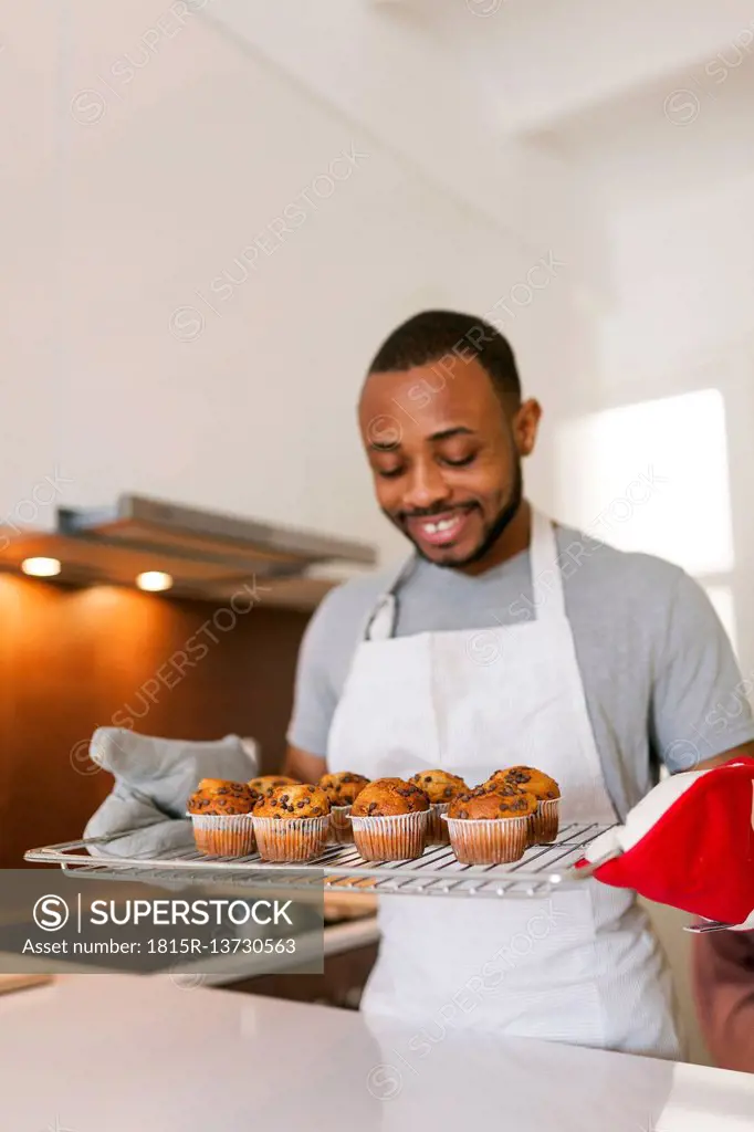 Young man baking cup cakes at home