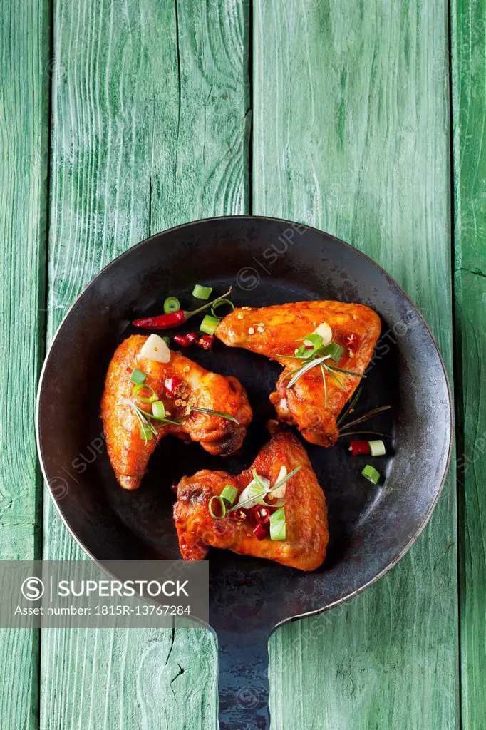 Three marinated and grilled chicken wings in cast-iron frying pan