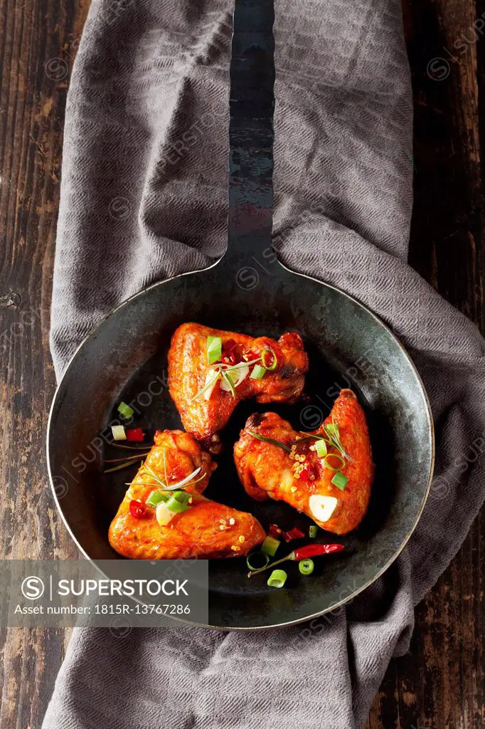 Three marinated and grilled chicken wings in cast-iron frying pan