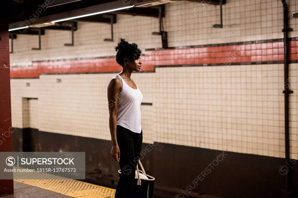 USA, New York City, Manhattan, woman with shopping bag waiting at subway station platform