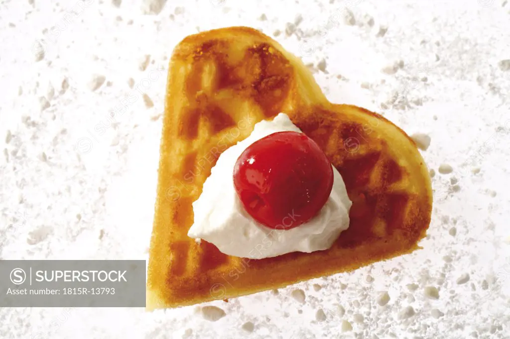 Heart shaped waffle decorated with cream and cherry, elevated view
