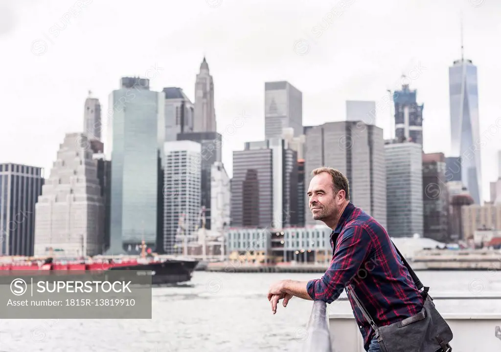 USA, New York City, man on ferry with Manhattan skyline in background