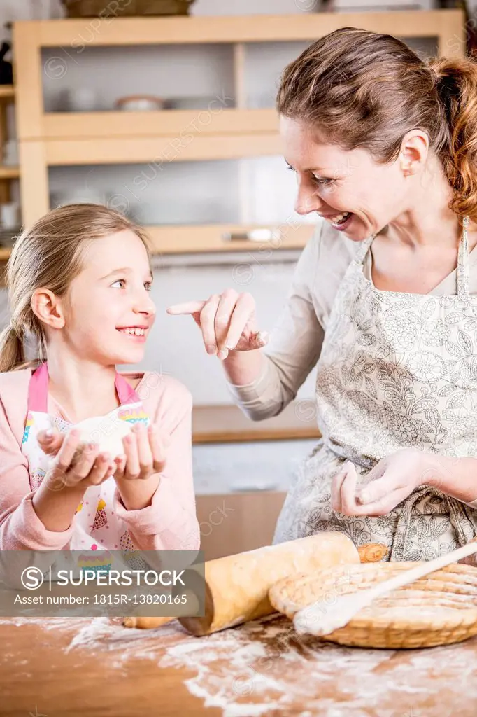 Mother and daughter baking bread in kitchen together