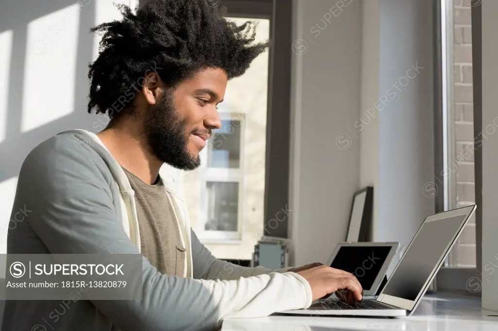 Man working in front of window at home with laptop