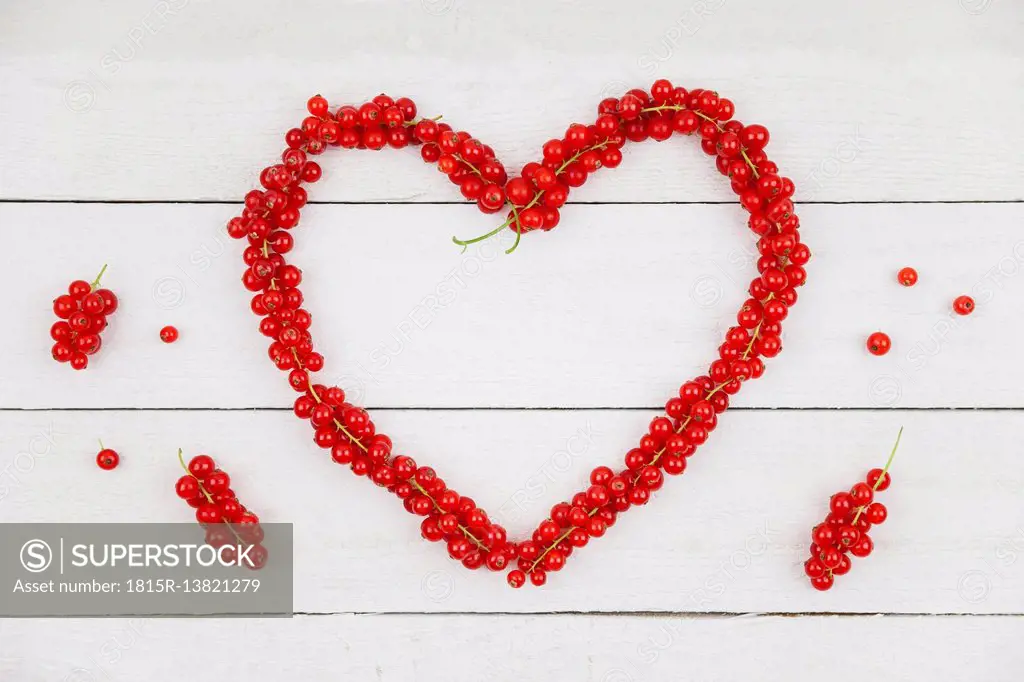 Heart shaped of red currants on white wood