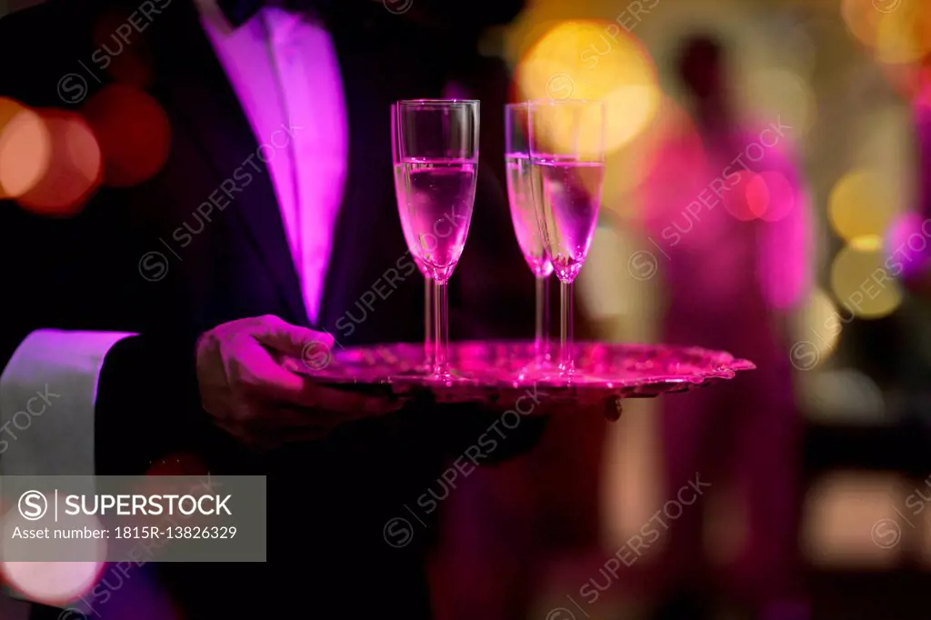 Waiter with tray serving champagne glasses on a party