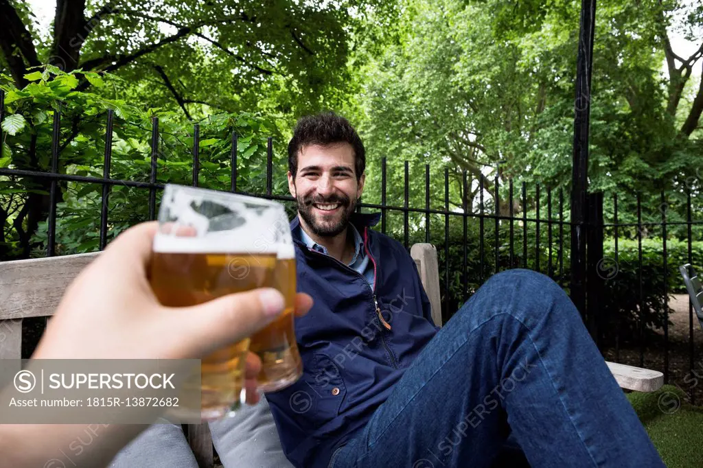 Portrait of smiling young man toasting with glass of beer in garden