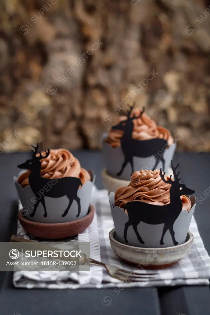 Cupcakes topped with chocolate buttercream and wrappers decorated with deers