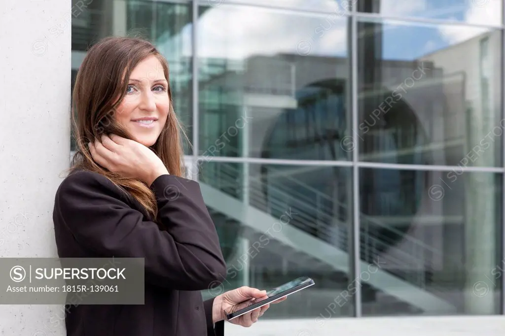 Germany, Berlin, Portrait of businesswoman holding digital tablet, smiling