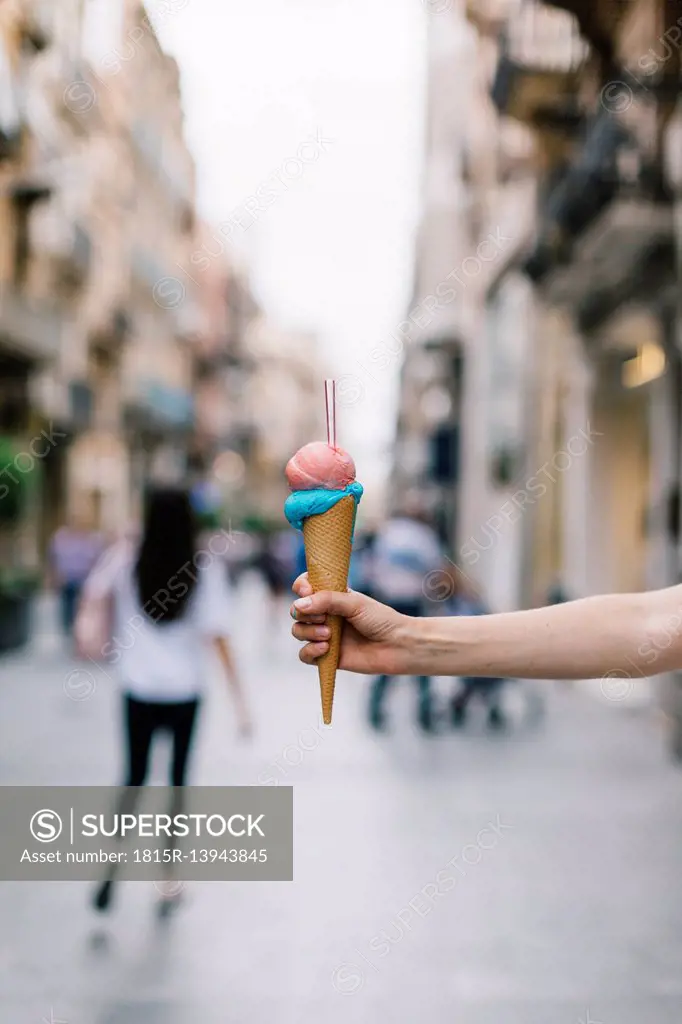 Close-up of woman holding ice cream conein shopping street