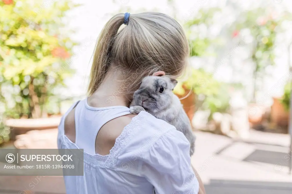 Girl cuddling with rabbit outdoors