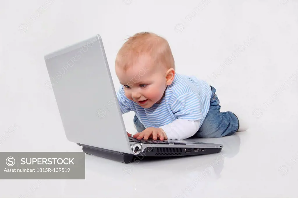 Baby boy using laptop on white background, smiling