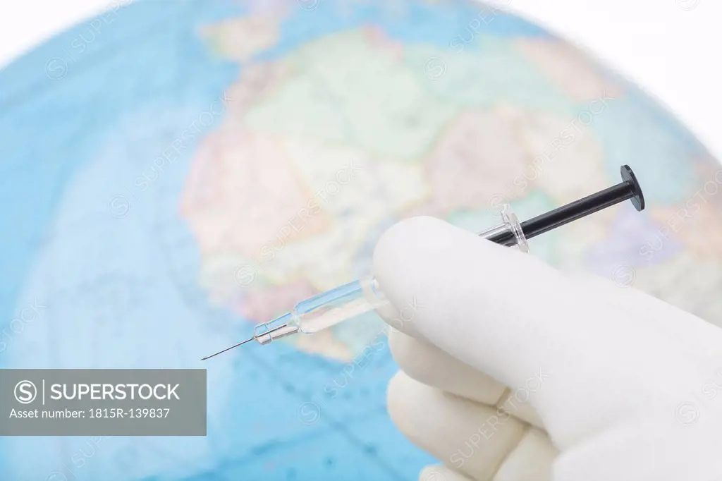Germany, Freiburg, Gloved hand holding vaccination syringe, close up