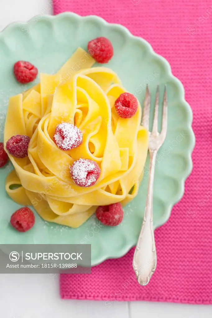 Homemade fettuccine with raspberries on plate, close up