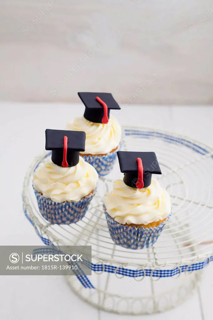 Graduation cupcakes with vanila frosting on cake stand, close up