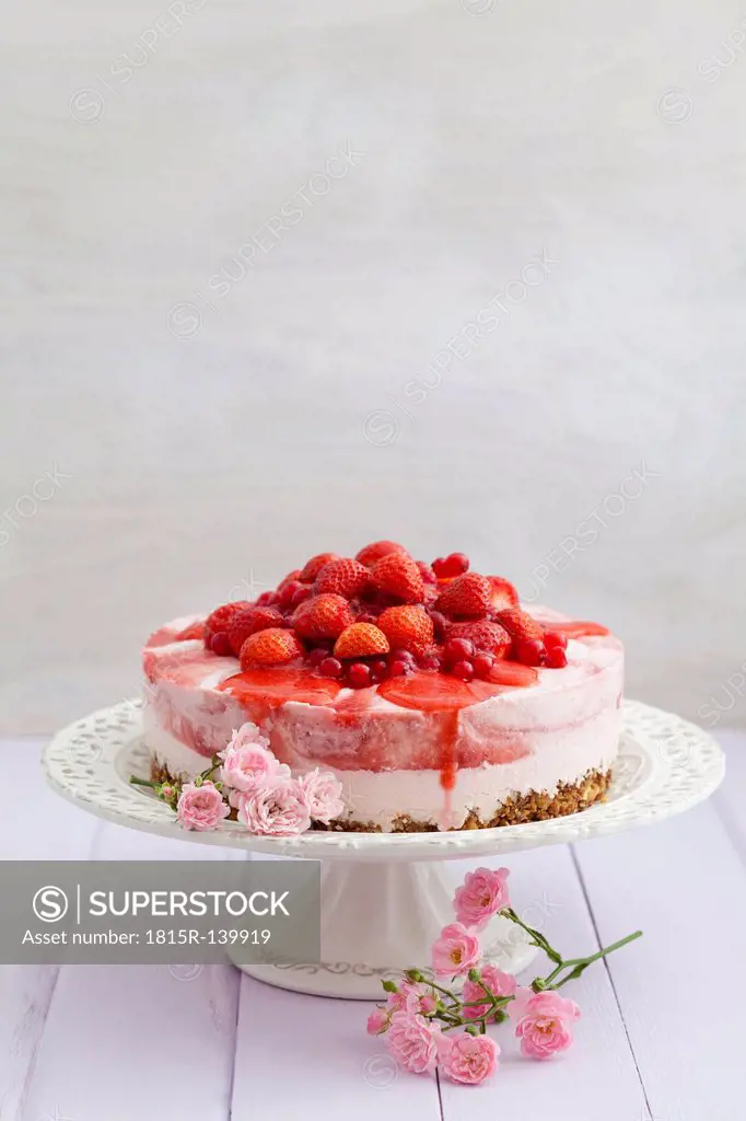 Strawberry cheesecake with fresh strawberries and redcurrants on wooden table, close up