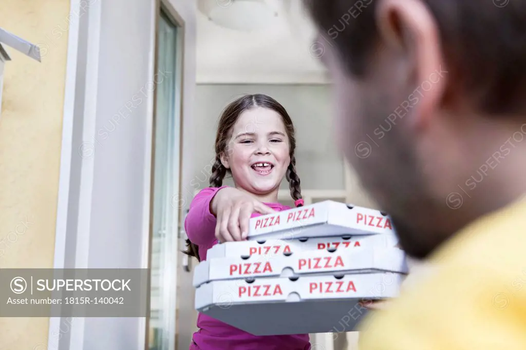 Germany, North Rhine Westphalia, Cologne, Girl taking pizza boxes from delivery man, smiling