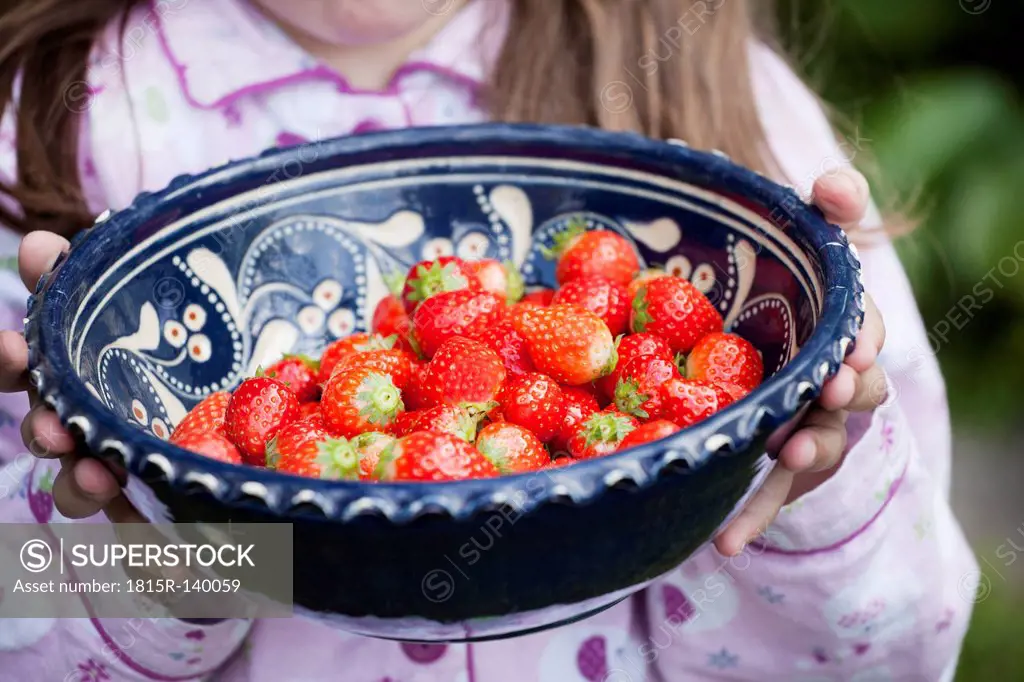 Germany, North Rhine Westphalia, Cologne, Girl holding bowl of strawberries, close up