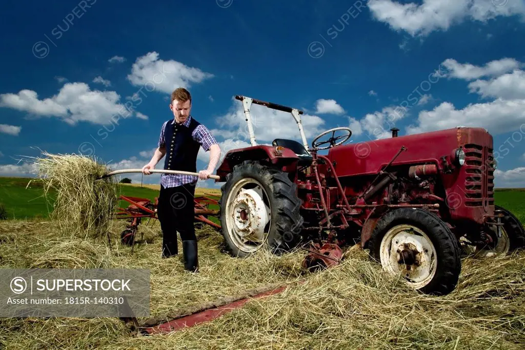 Germany, Bavaria, Farmer with rake in field