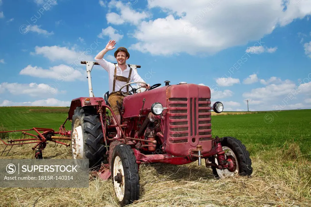 Germany, Bavaria, Farmer in tractor and waving, smiling