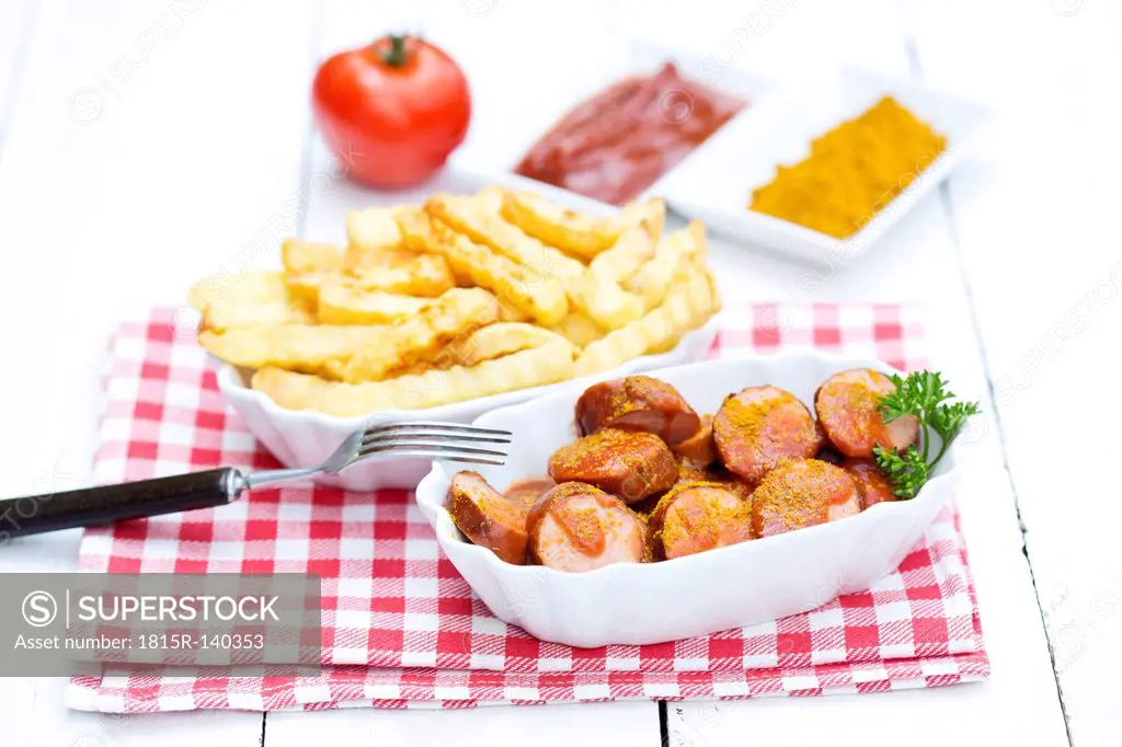 Bowl of sausages with french fries, currywurst and ketchup on wooden table, close up