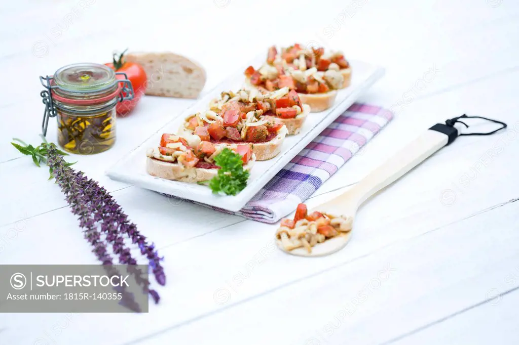 Plate of bruschetta with tomatoes, white shimeji mushrooms, herbs and olive oil on wooden table, close up