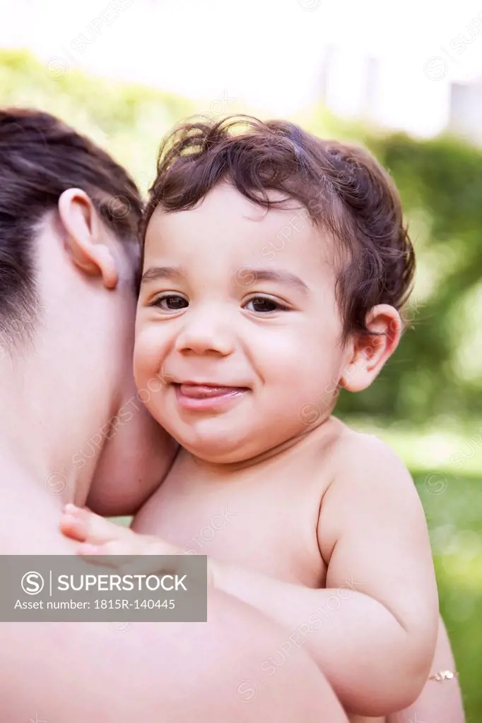 Mother cuddling her baby boy, smiling
