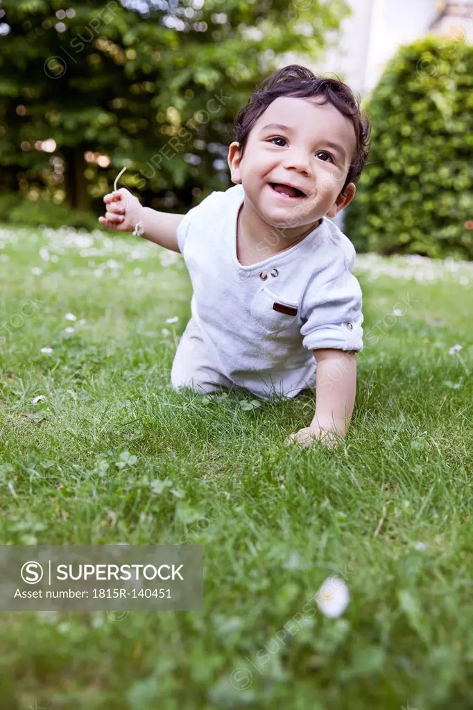 Baby boy crawling on grass, smiling