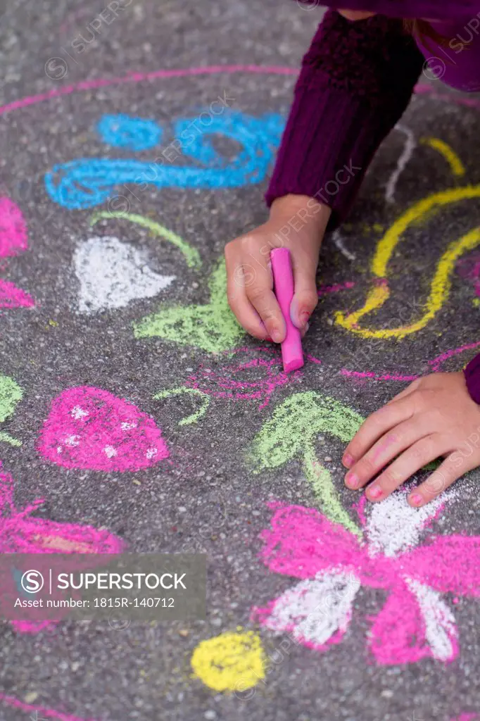 Germany, Girl drawing on street with chalk