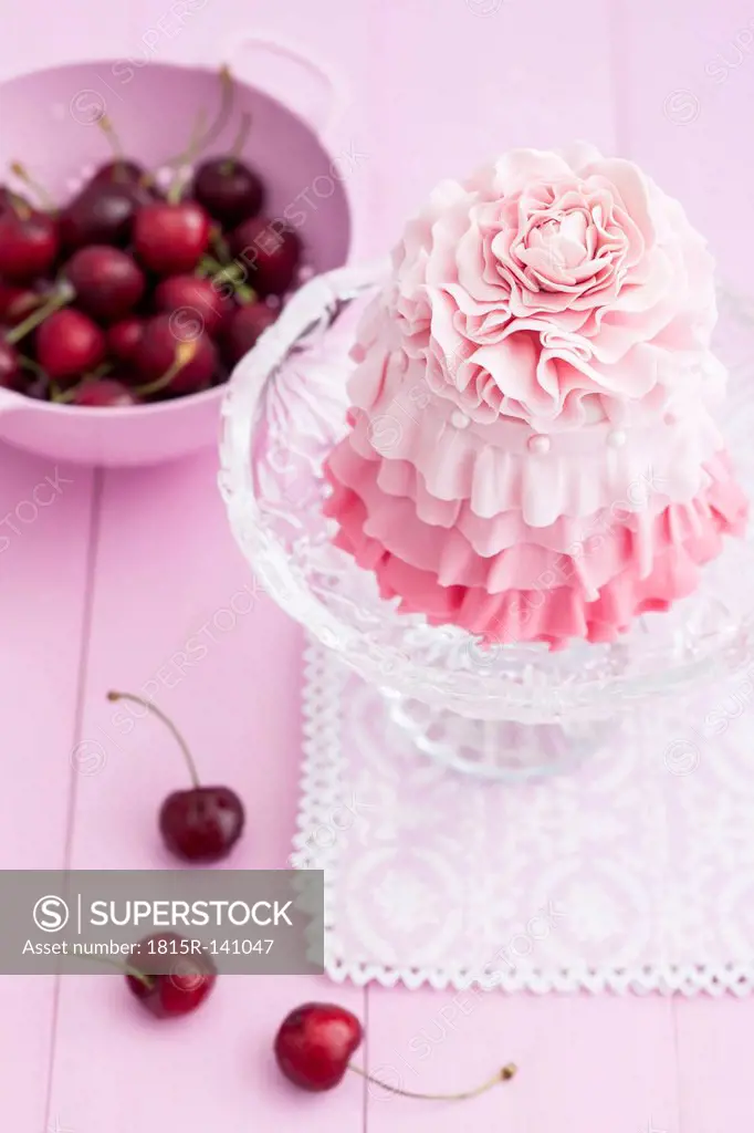 Pink mini cake on cakestand with cherries
